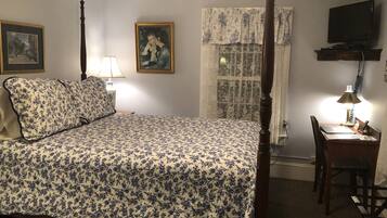 Un dormitorio con cama con dosel, un escritorio con silla, un televisor y dos cuadros en la pared.