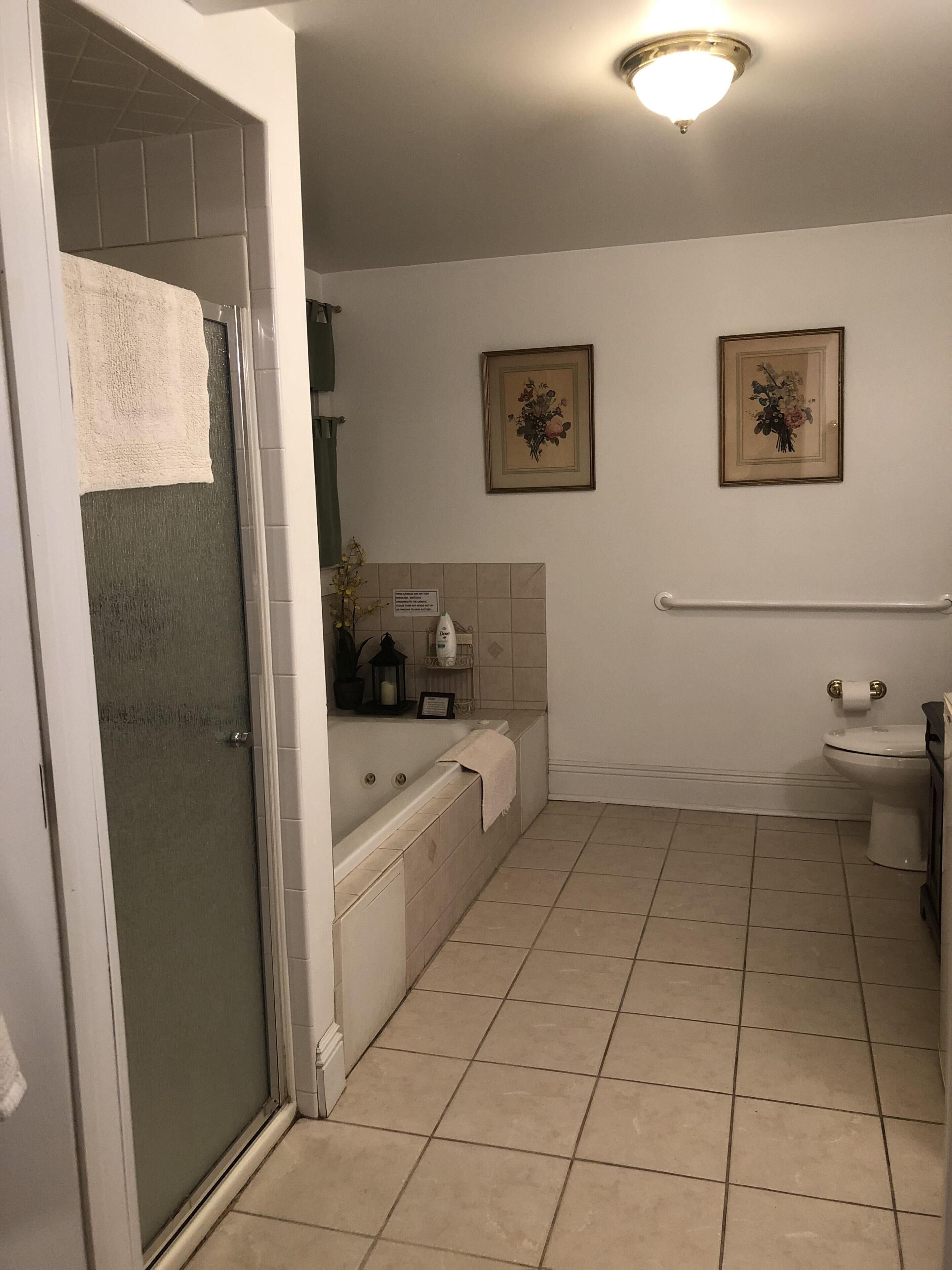 Kylpyhuoneessa on kylpyamme, wc ja suihku. Seinällä on kaksi kehystettyä kuvaa.