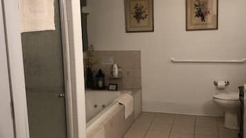 A bathroom with a bathtub, toilet, and shower. There are two framed pictures on the wall.