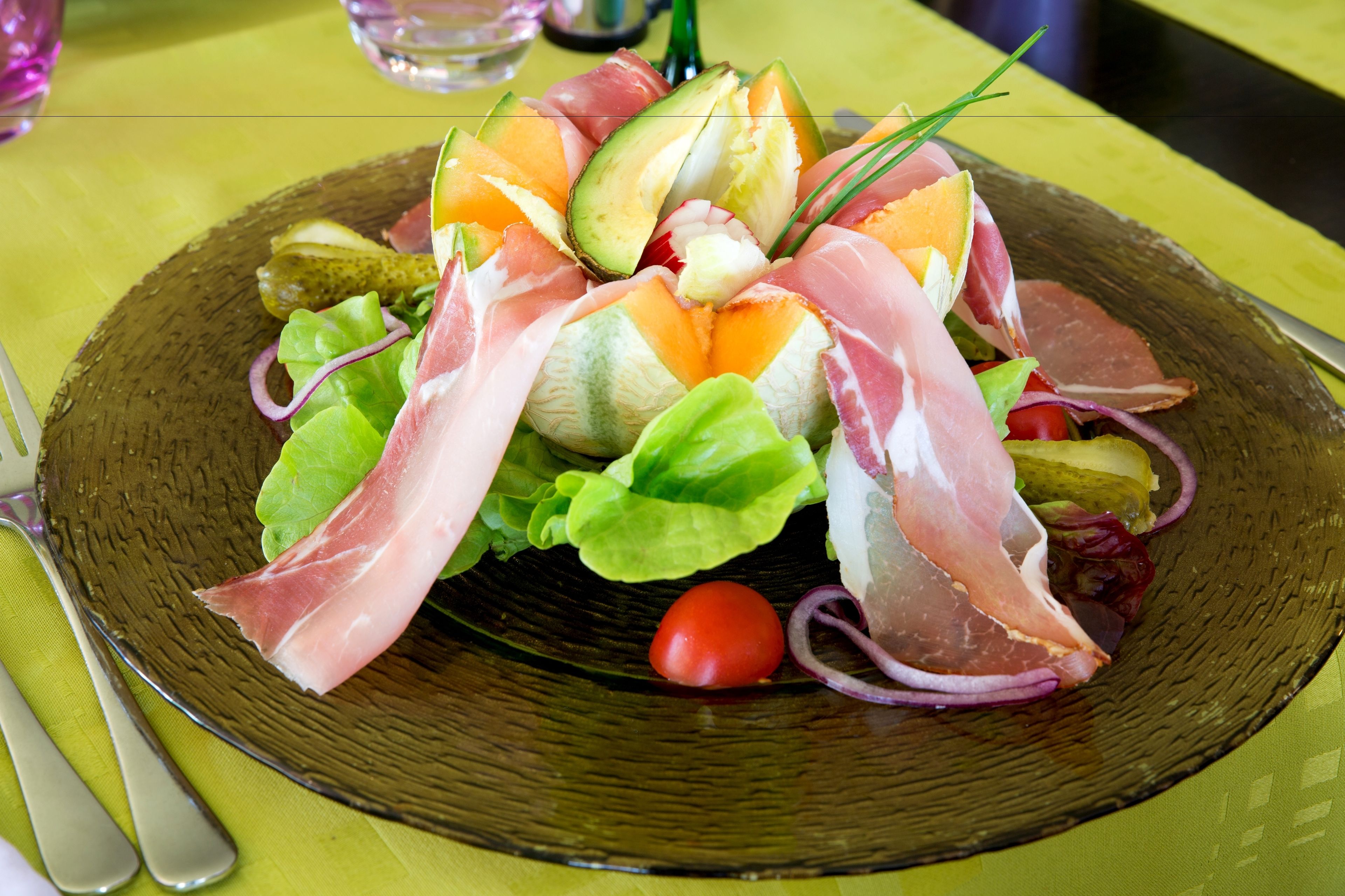 Een salade met diverse groenten en vleessoorten op een bord.