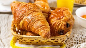 A basket of croissants on a table with a yellow cloth. - Au Relais D'Alsace (Rouffach)
