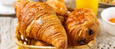 A basket of croissants on a table with a yellow cloth.