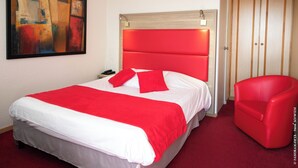 A hotel room with a large bed, a red chair, a painting on the wall, and a wooden wardrobe. - Au Relais D'Alsace (Rouffach)