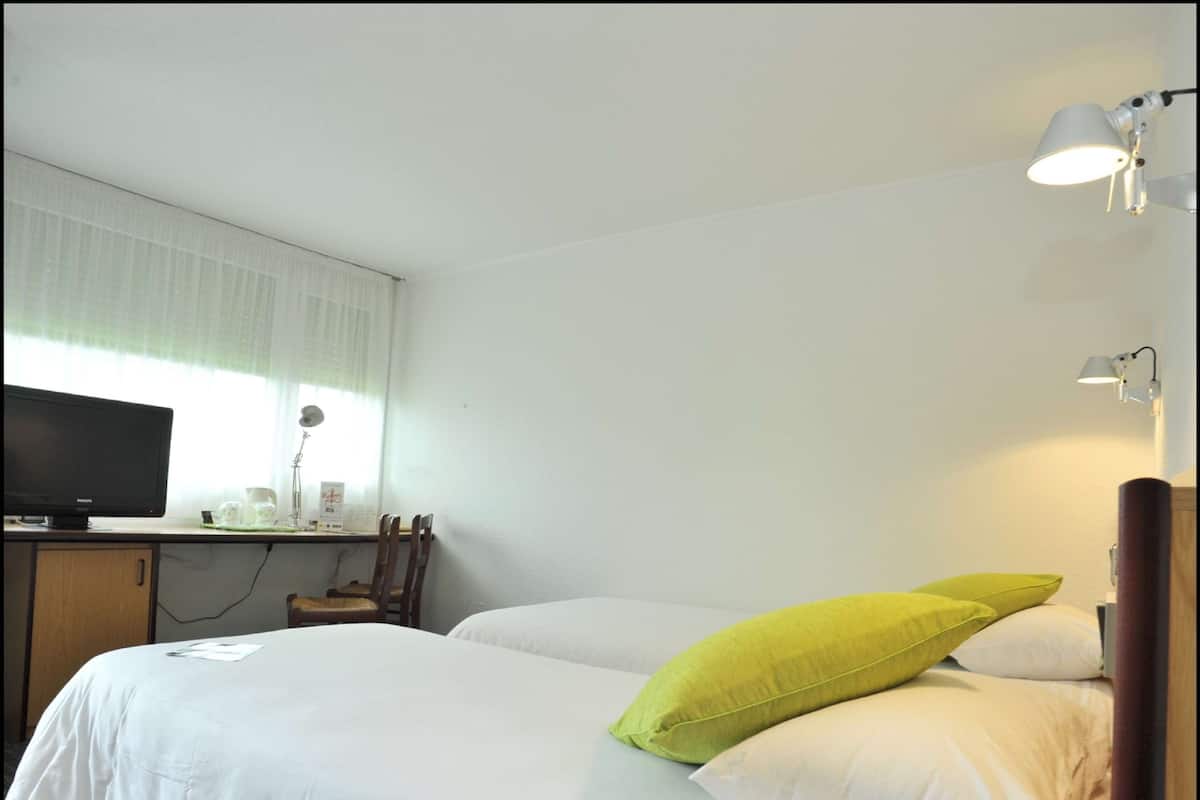 Une chambre d’hôtel comprenant un lit, un bureau avec un ordinateur, une lampe et un téléviseur.