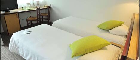 Habitación de hotel con dos camas, un escritorio con computadora, una silla y una lámpara.