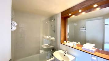 A bathroom with a glass-enclosed shower, a sink, and a mirror with a wooden frame.