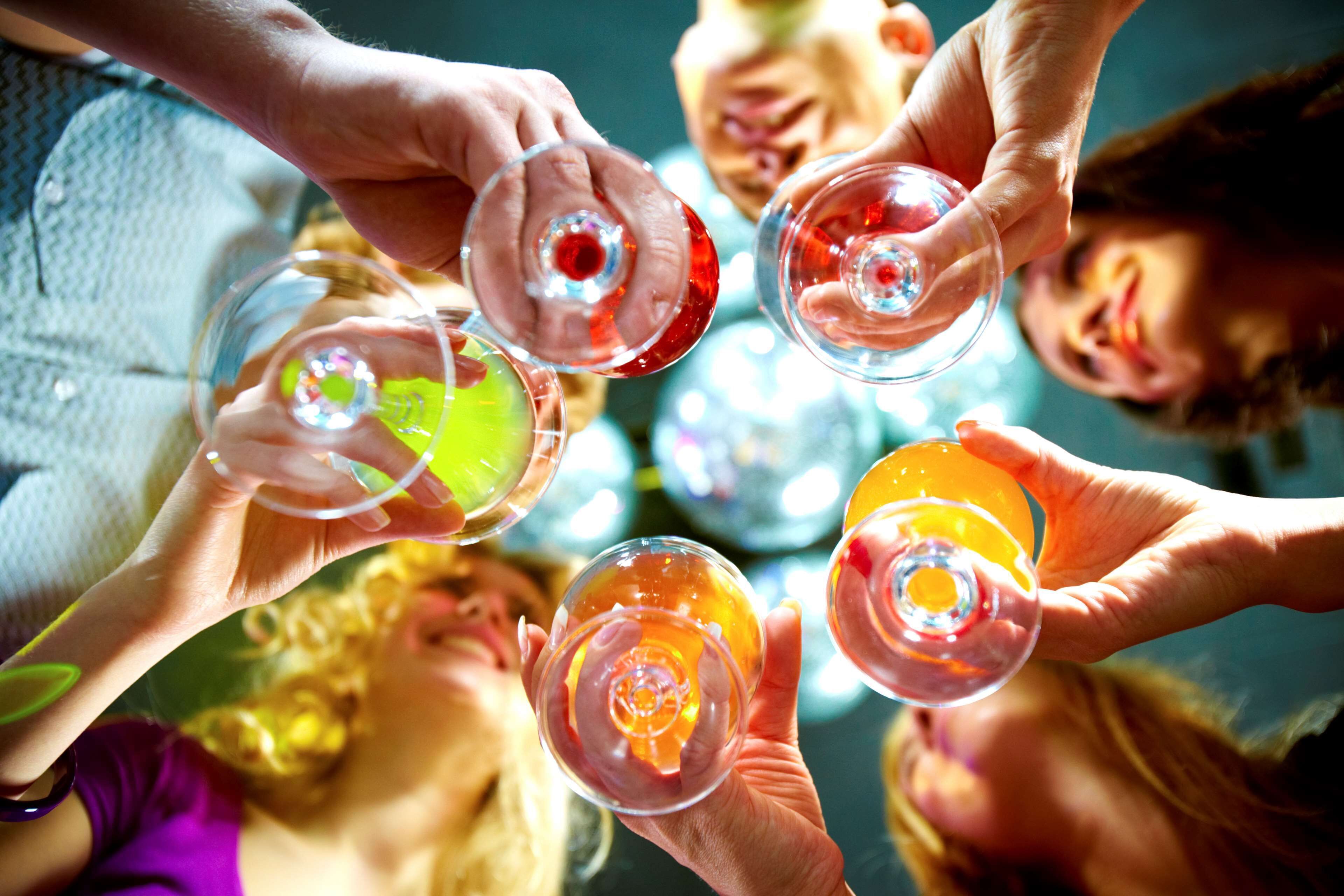 A group of people holding glasses with colorful drinks, suggesting a social gathering or celebration.