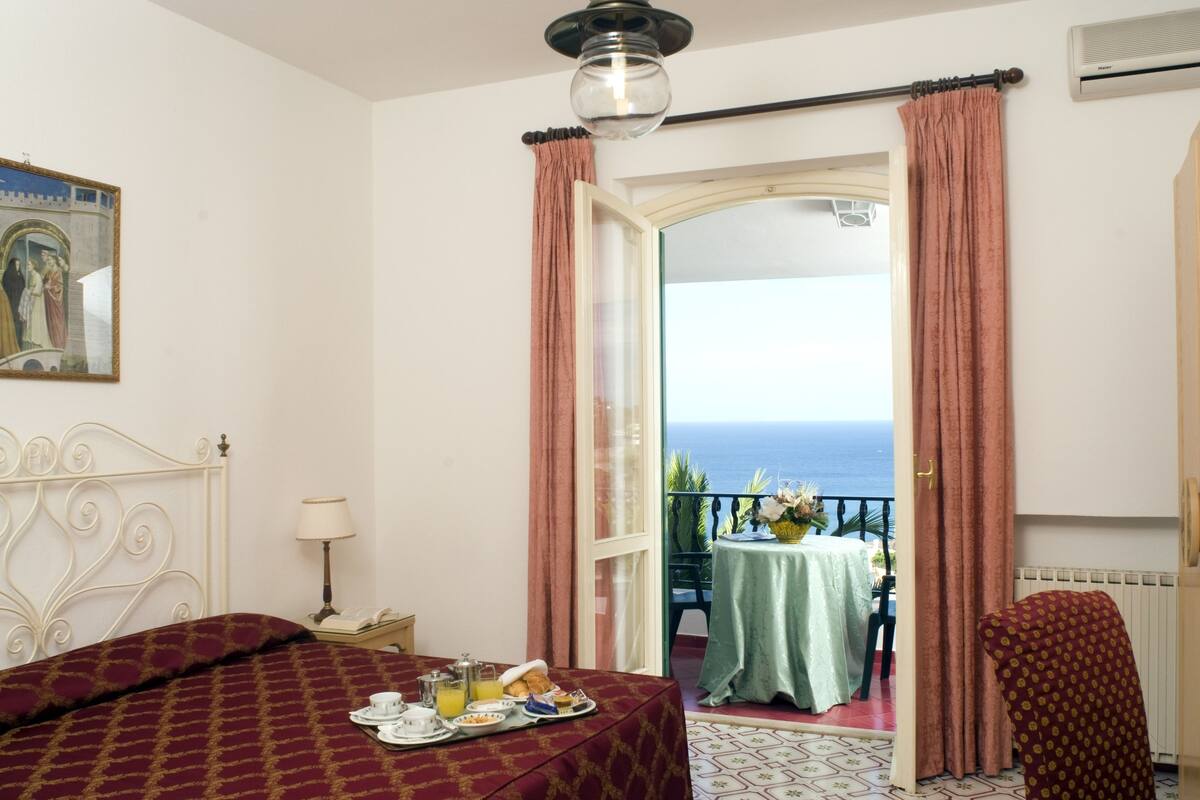 Une chambre d’hôtel avec un lit, un plateau de petit-déjeuner et une vue sur la mer.