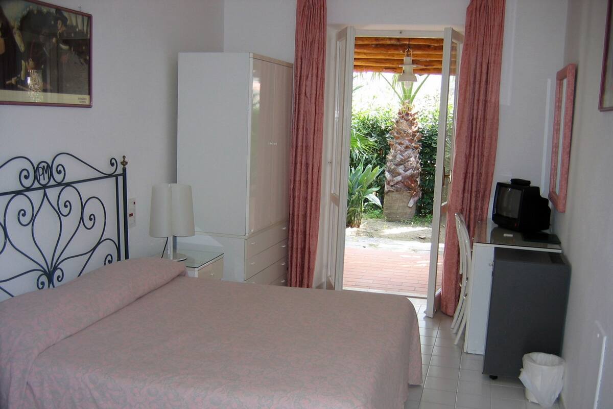 Une chambre à coucher comprenant un lit, un bureau, une télévision et une armoire.