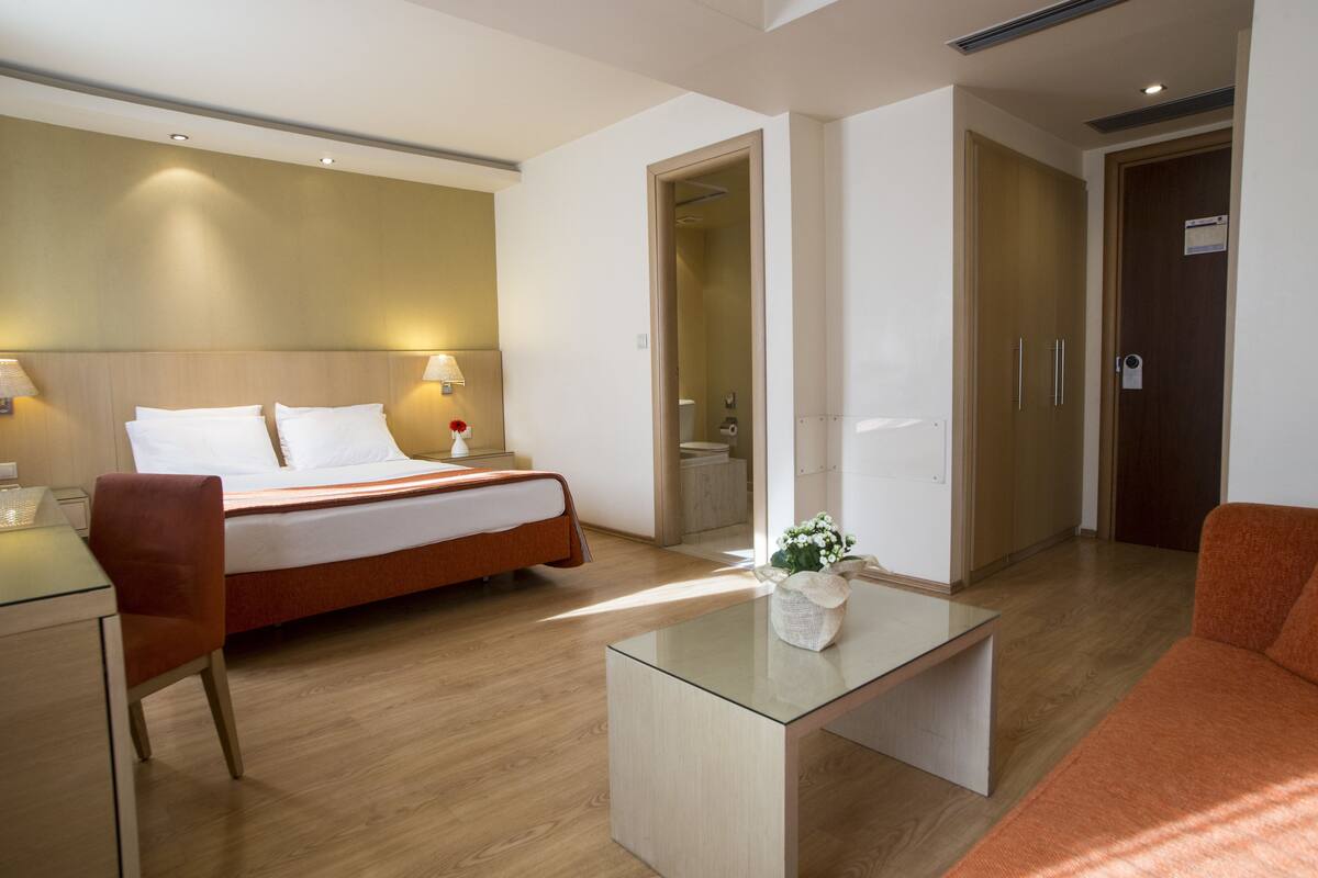 Een hotelkamer met een bed, een bureau, een stoel, een glazen salontafel en een bank.