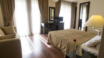 A hotel room with a bed, a desk, a chair, and a lamp.