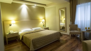 Une chambre d’hôtel avec un lit, des lampes de chevet, une chaise, une table avec une assiette et des verres, et un miroir.