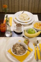 A dining table with plates of food, a cup of coffee, a glass of orange juice, and a banana.