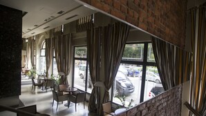 Un café aux murs de briques, avec de grandes fenêtres et une vue sur les voitures garées à l’extérieur.