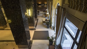 Un hall d’hôtel doté d’un sol en marbre, d’un espace salon et de grandes fenêtres.