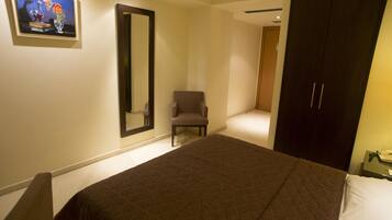 A bedroom with a large bed, a chair, a wardrobe, and a painting on the wall.