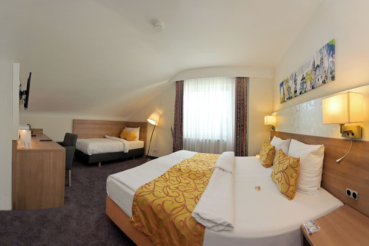 Une chambre d’hôtel avec deux lits, un bureau et une grande fenêtre avec des rideaux.