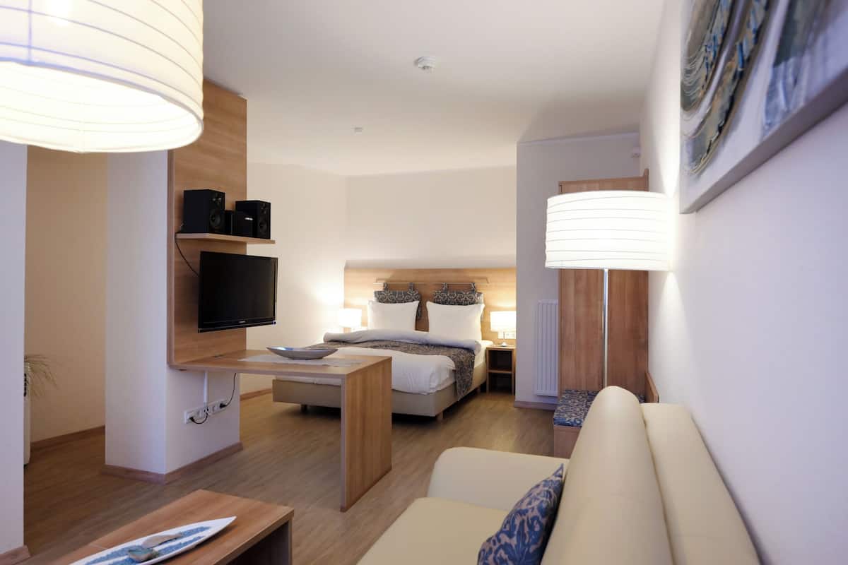 Une chambre d’hôtel moderne équipée d’un lit, de tables de chevet, d’un téléviseur et d’un canapé.