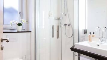 Ein modernes Badezimmer mit einer Duschkabine, einem weißen Waschbecken und einer Toilette.