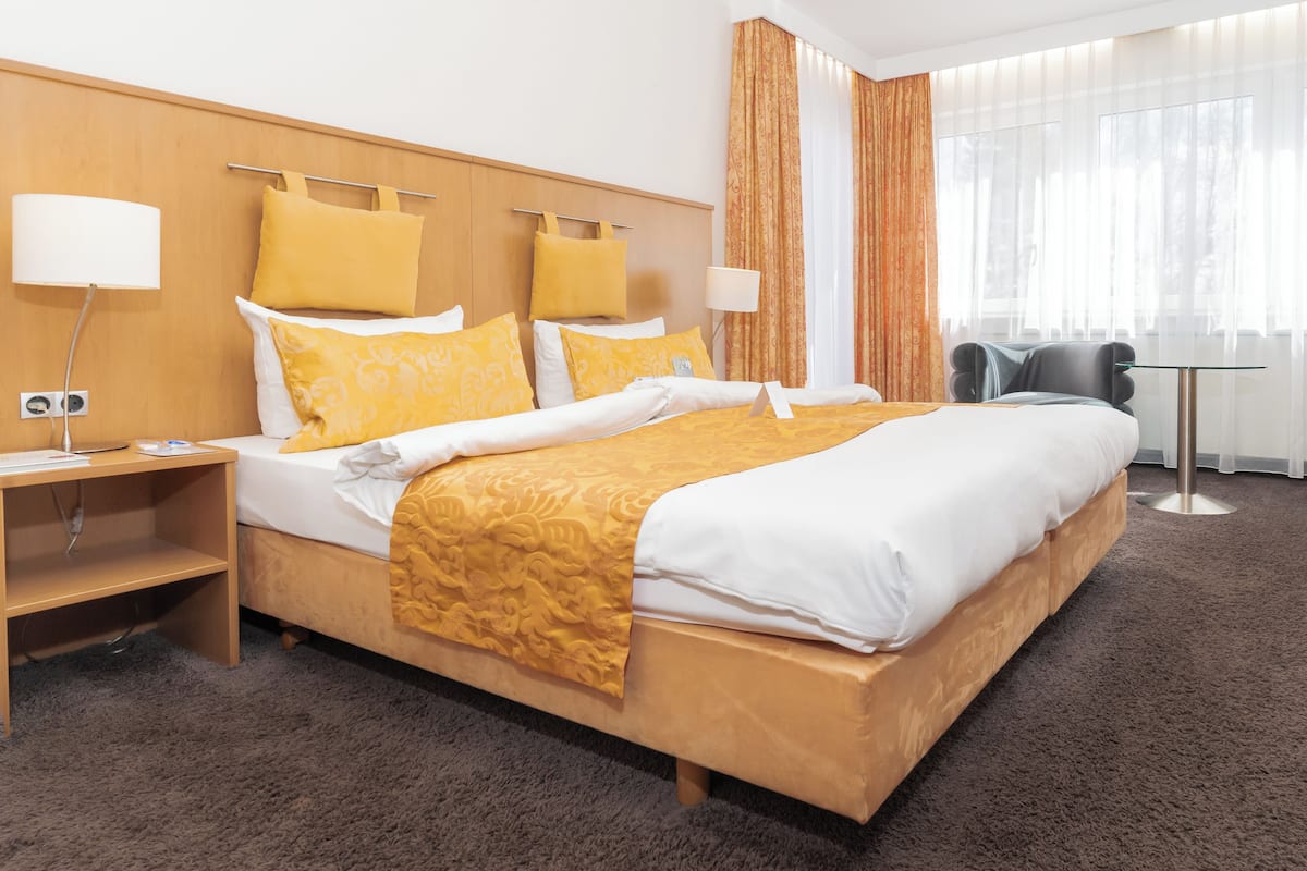 Une chambre d’hôtel avec un grand lit, deux tables de chevet, un bureau et une chaise.