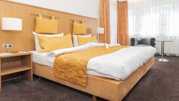 Ein Hotelzimmer mit einem großen Bett, zwei Nachttischen, einem Schreibtisch und einem Sessel.