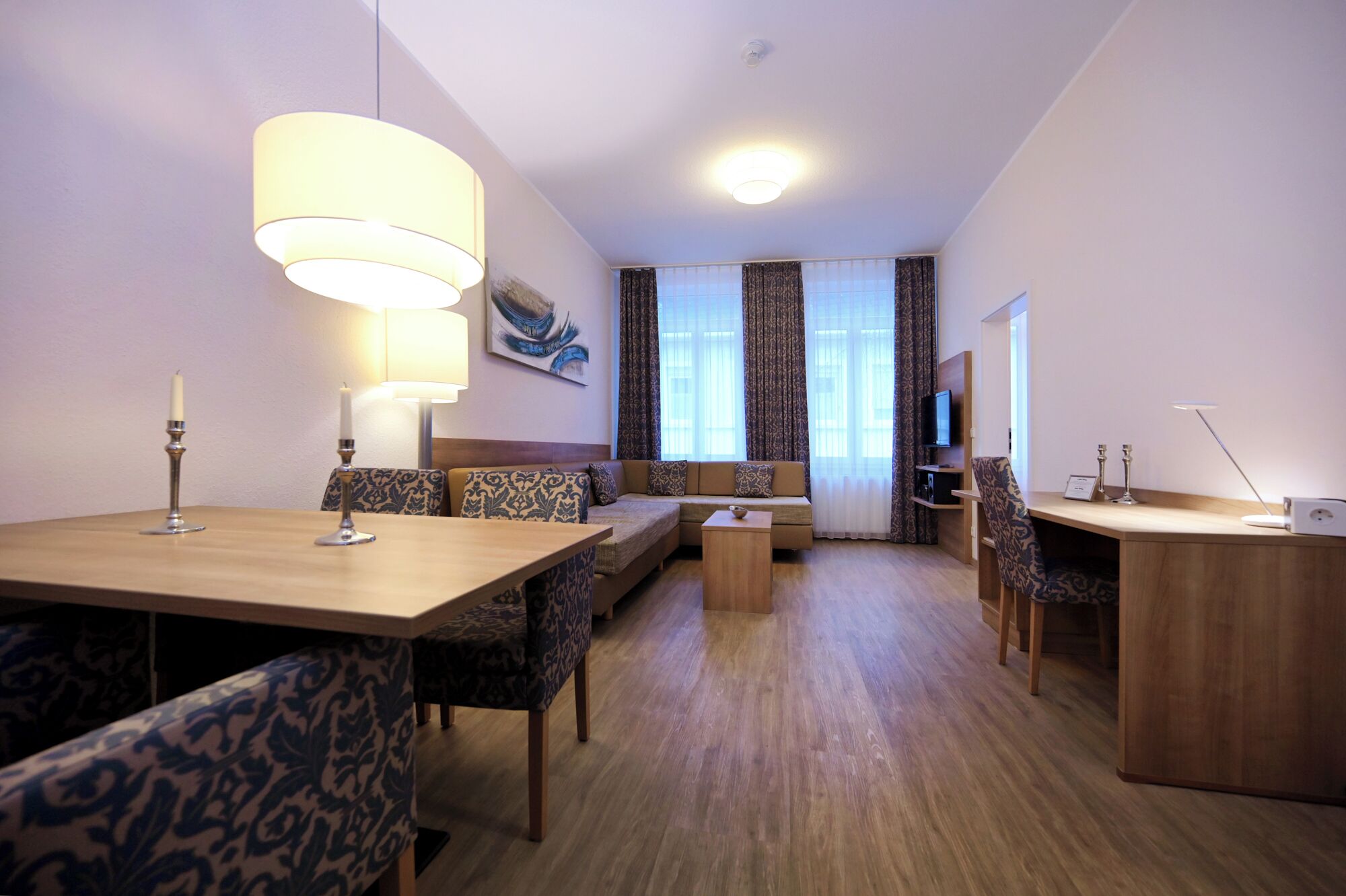 Ein Hotelzimmer mit Essbereich, einer Couch, einem Fernseher und einem Schreibtisch.