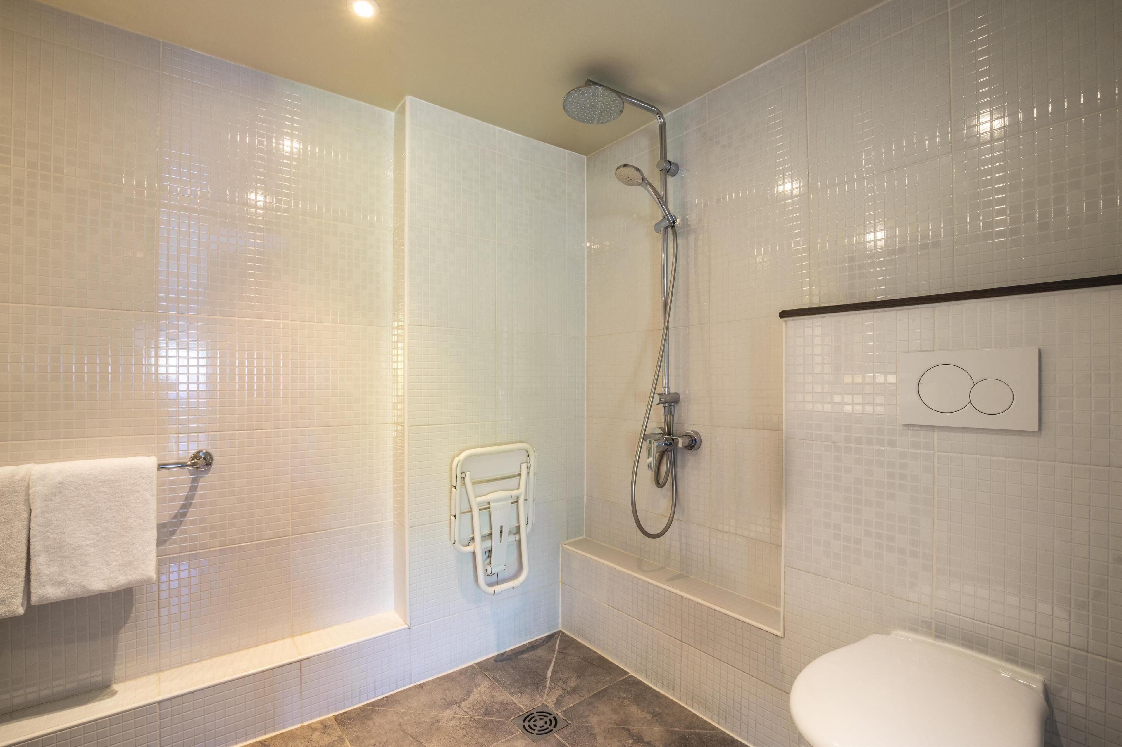Un baño moderno con ducha a ras de suelo, inodoro y perchero.