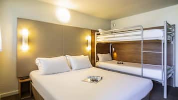 Ein Hotelzimmer mit einem Etagenbett, einem Nachttisch mit Fernbedienung und einer Zeitschrift auf dem Bett.