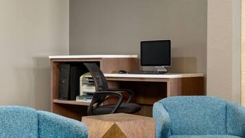 A modern office space with a desk, computer, and two blue chairs.