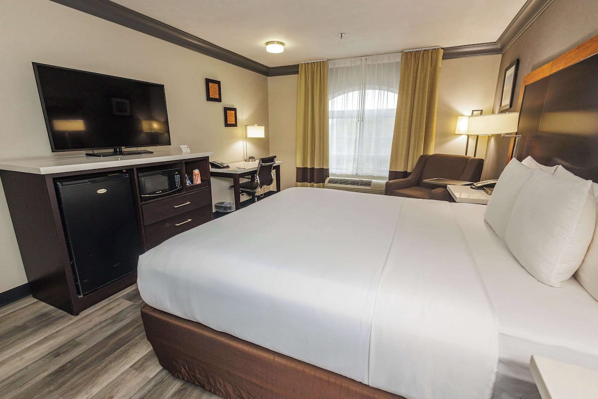 Une chambre d’hôtel avec un grand lit, un bureau avec un ordinateur, une télévision et un minibar.