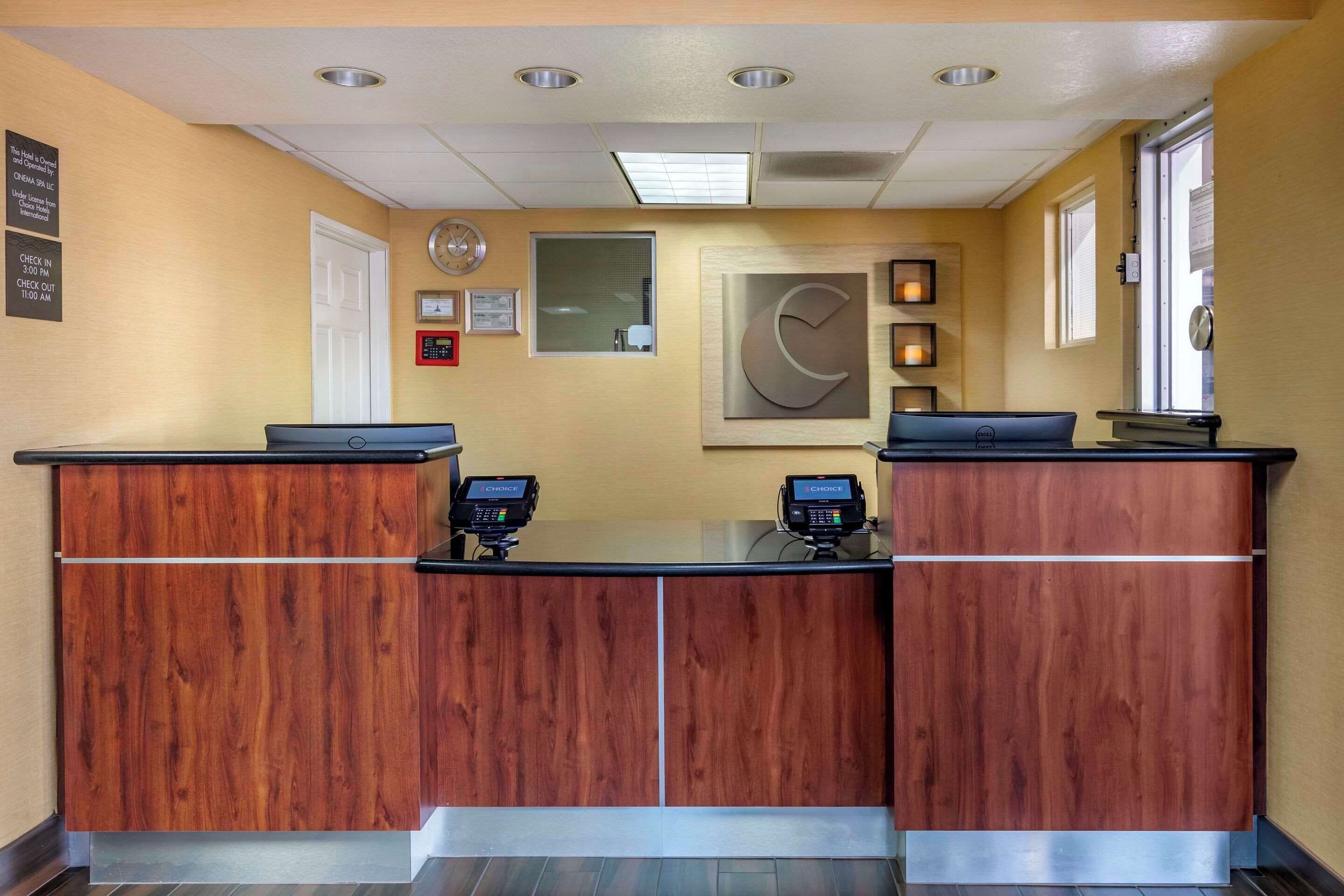 Una recepción con dos mostradores, un reloj, certificados enmarcados y un reloj de pared.