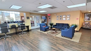 A reception area with a reception desk, blue sofas, a coffee table, and a display of magazines.
