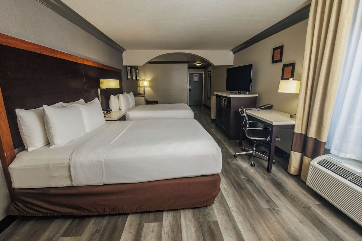 Une chambre d’hôtel avec un grand lit, un bureau, une chaise, une télévision et un radiateur.