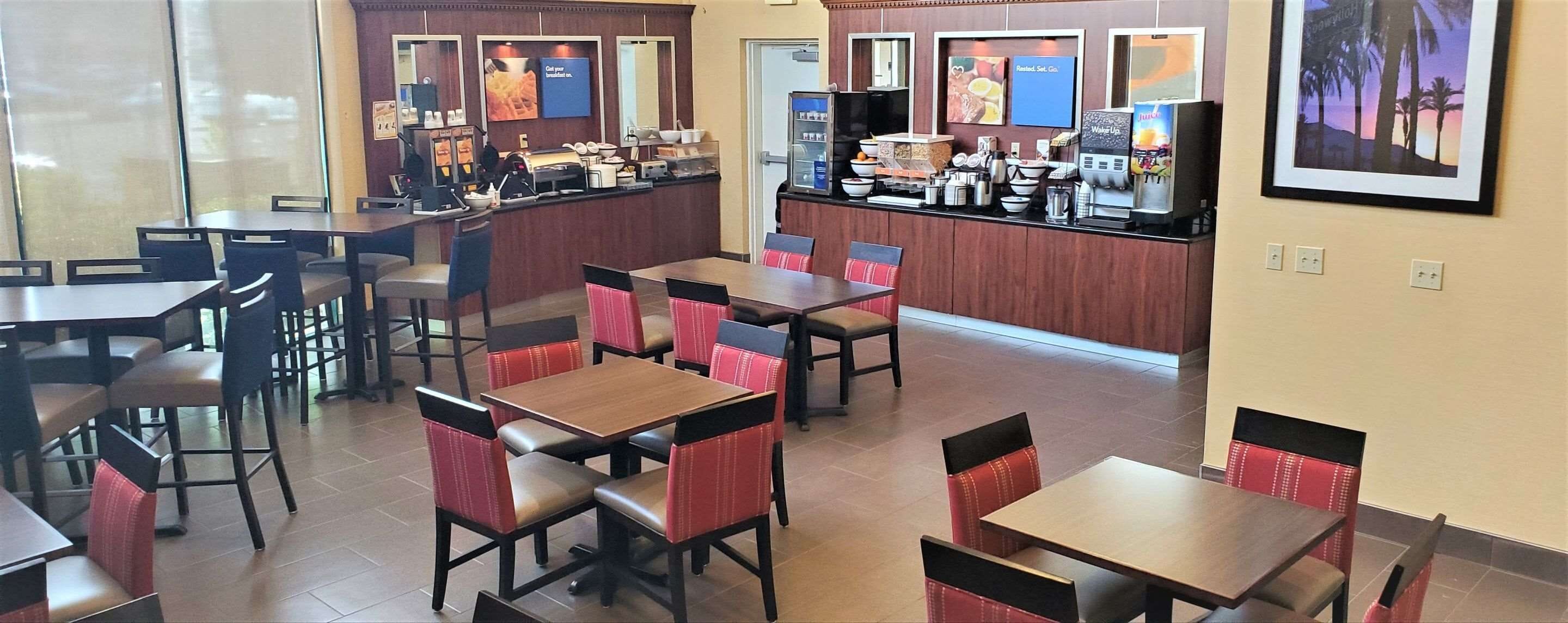 Un ristorante con diversi tavoli e sedie, un bancone con una macchina per caffè e una lavagna con il menu.
