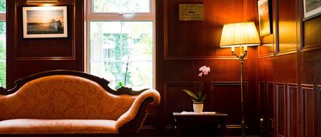 A room with a sofa, a lamp, a framed picture, and a sign indicating amenities.
