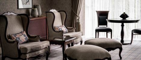 A traditional room with a patterned carpet, a sofa set, a small table, and a round table with chairs.