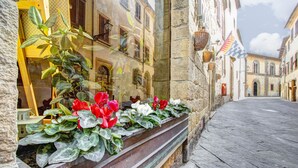 Un estrecho callejón con edificios de piedra, un banco de madera con flores y un camino adoquinado.