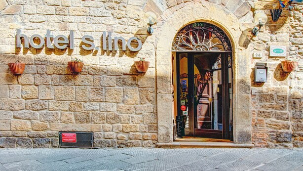 Un edificio de piedra con un letrero que dice "hotel s.ino" y una puerta con una reja de hierro forjado.