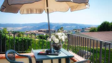 Un balcone con tavolo, sedie e ombrellone.