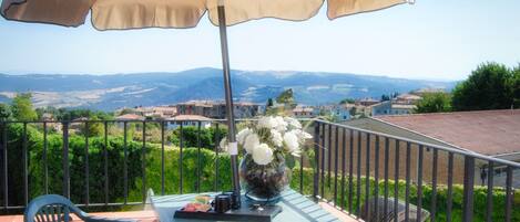 Un balcon avec une table, des chaises et un parasol.