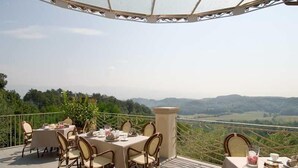 Un espace extérieur aménagé pour les repas, avec des tables et des chaises, offrant une vue sur un paysage pittoresque.