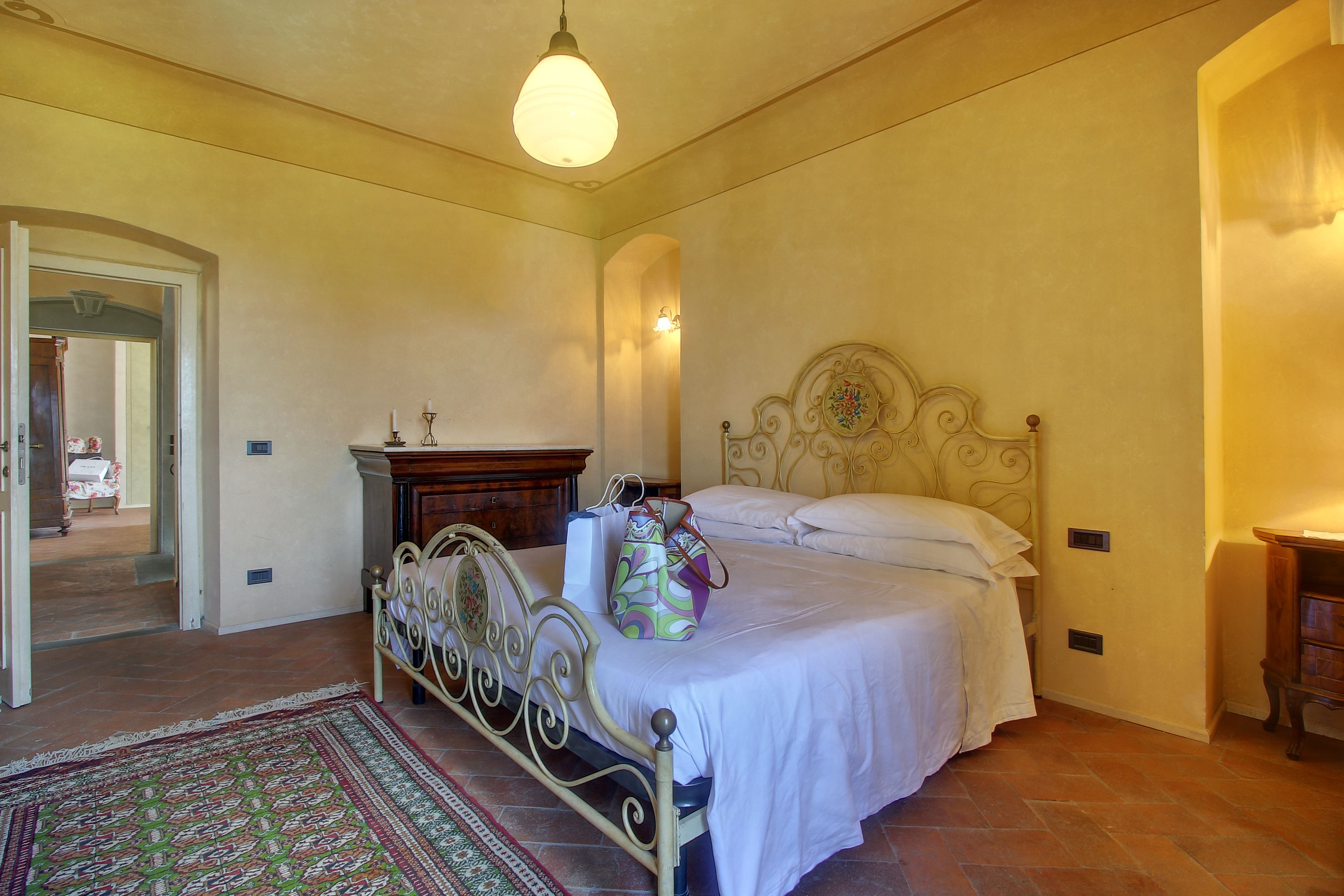 A bedroom with a bed, bedside table, lamp, and a rug.