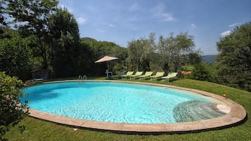 Een buitenzwembad, ligstoelen bij het zwembad