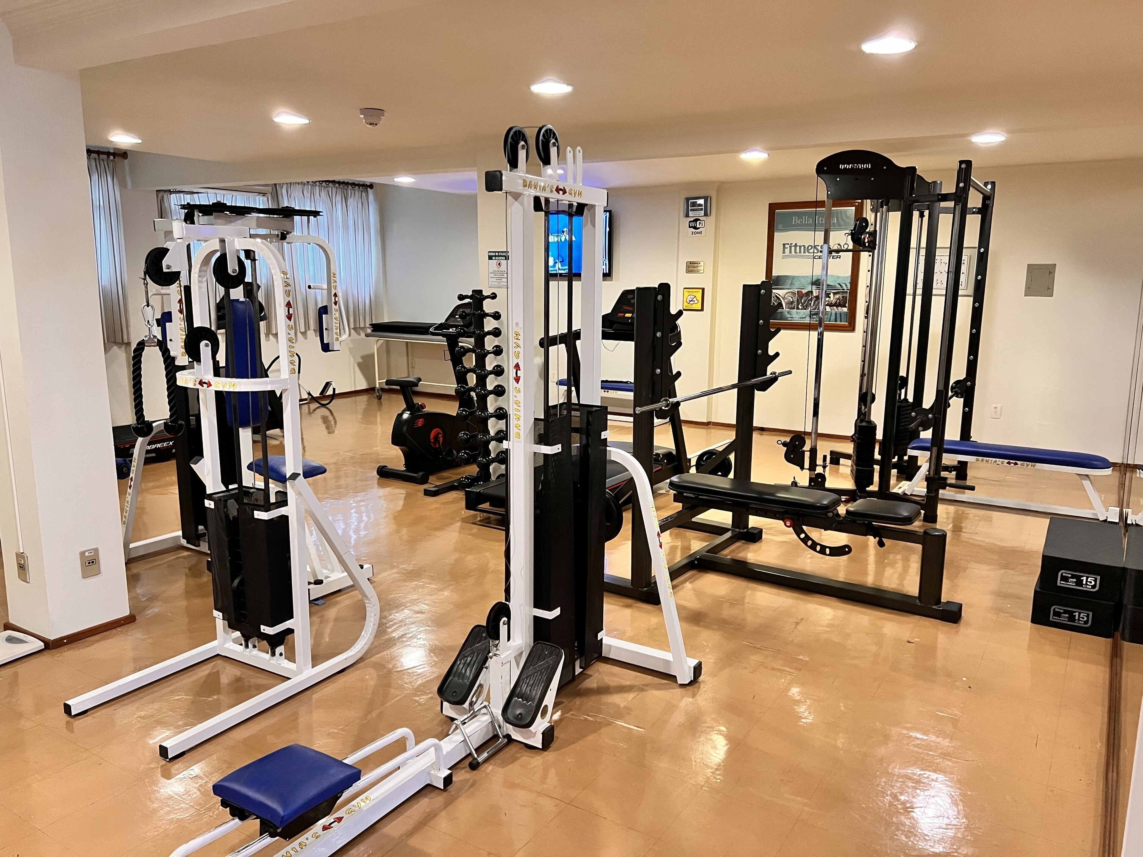Un gimnasio con diversos equipos de ejercicio, incluyendo una cinta de correr, máquinas de pesas y una banca.