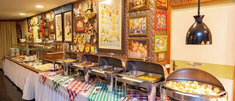 A buffet setup with various food stations, a checkered tablecloth, and a wall decorated with framed pictures and artifacts.