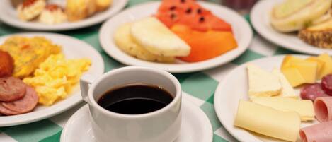 A breakfast table with plates of food, a cup of coffee, and a glass of juice.