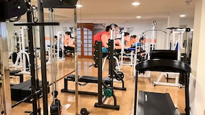 Un gimnasio con diversos equipos de ejercicio, incluyendo máquinas de pesas y una cinta de correr.
