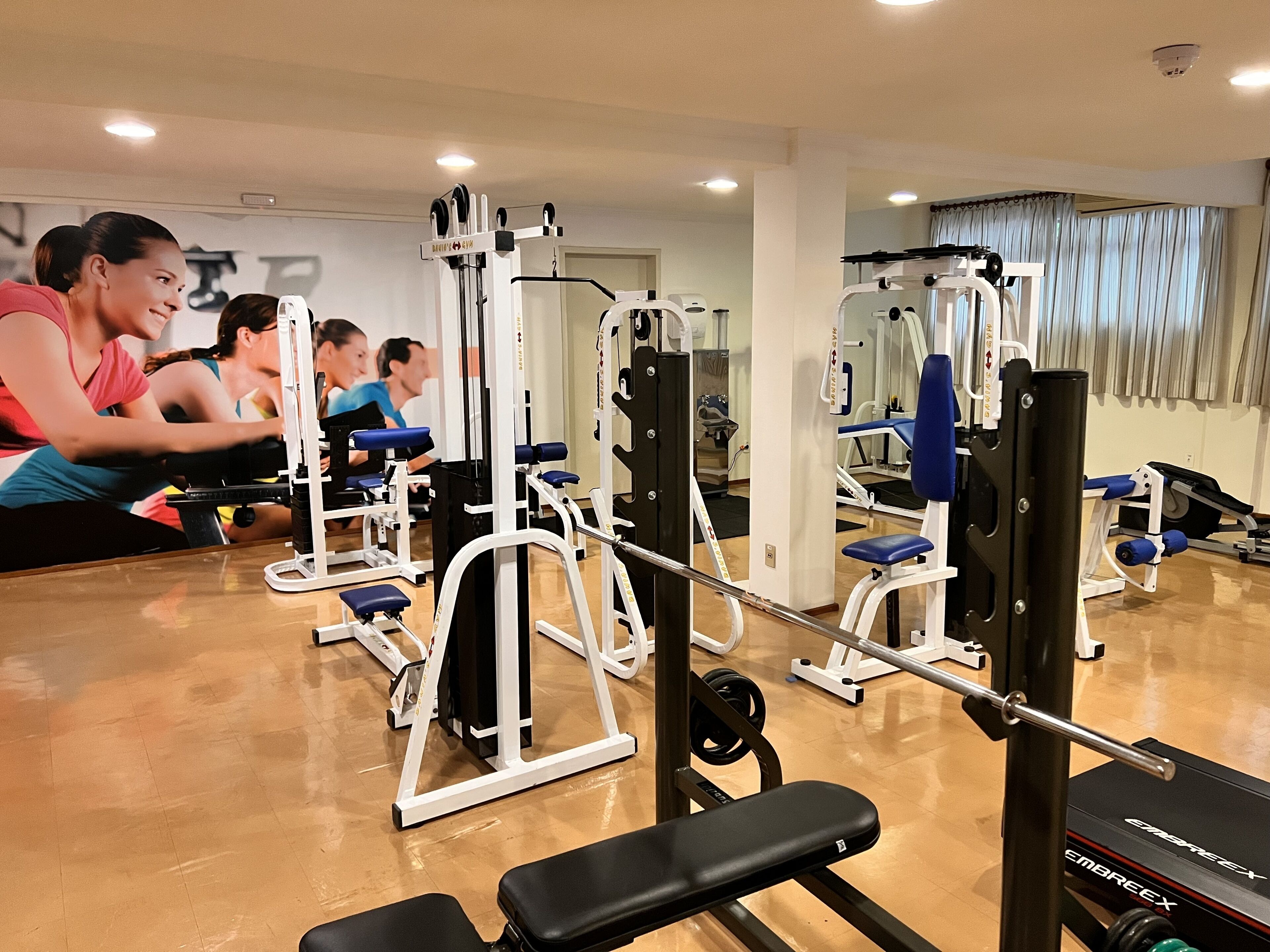 Un gimnasio con diversas máquinas de ejercicio, bancos y pesas.