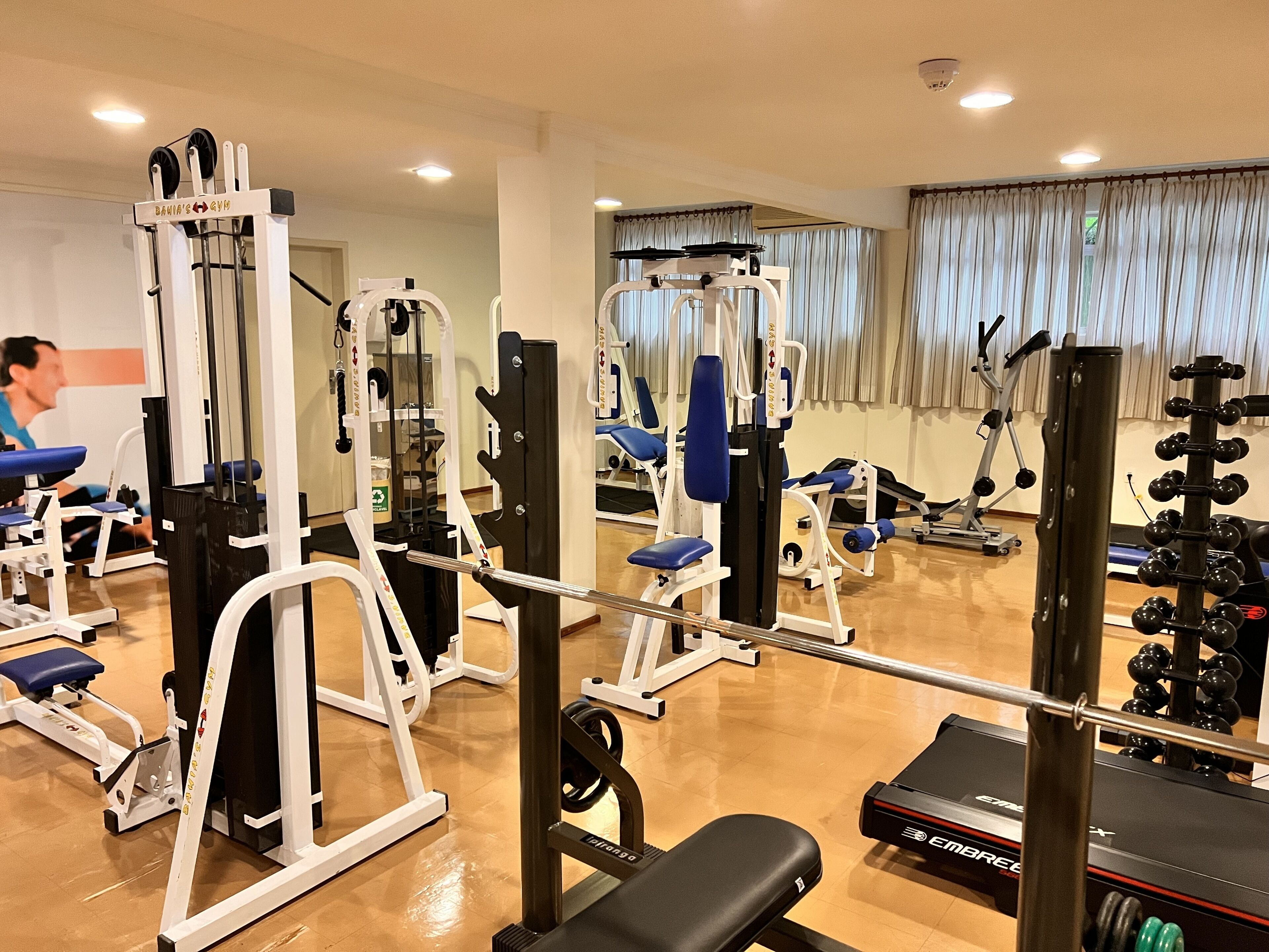 Une salle de sport équipée de divers appareils d’exercice, d’un banc et de supports à poids.