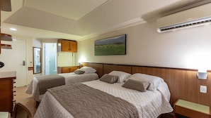 Habitación de hotel con dos camas, cabecera de madera, un cuadro en la pared y una mesita de noche con lámpara.